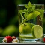Clear mug on a table with water, mint, and lime in it - 10 ways to detox