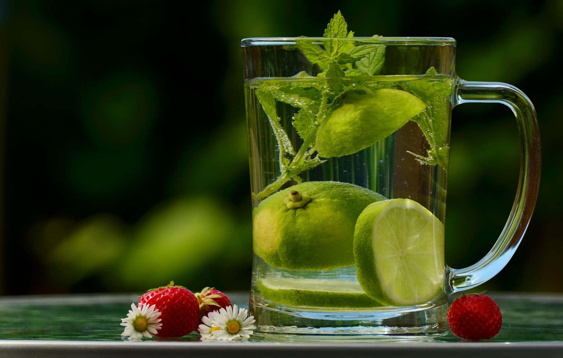 Clear mug on a table with water, mint, and lime in it - 10 ways to detox