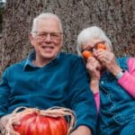 Couple sitting on a bench smiling and being goofy - photo is for What to Expect with Sex Hormones During Menopause