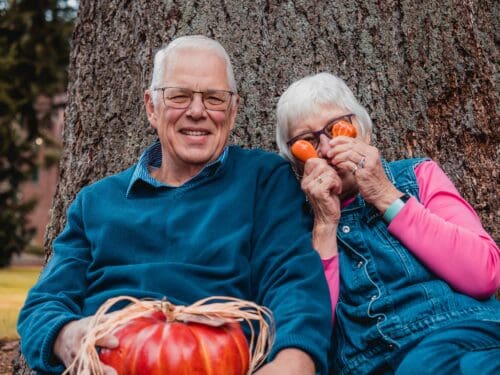 Couple sitting on a bench smiling and being goofy - photo is for What to Expect with Sex Hormones During Menopause